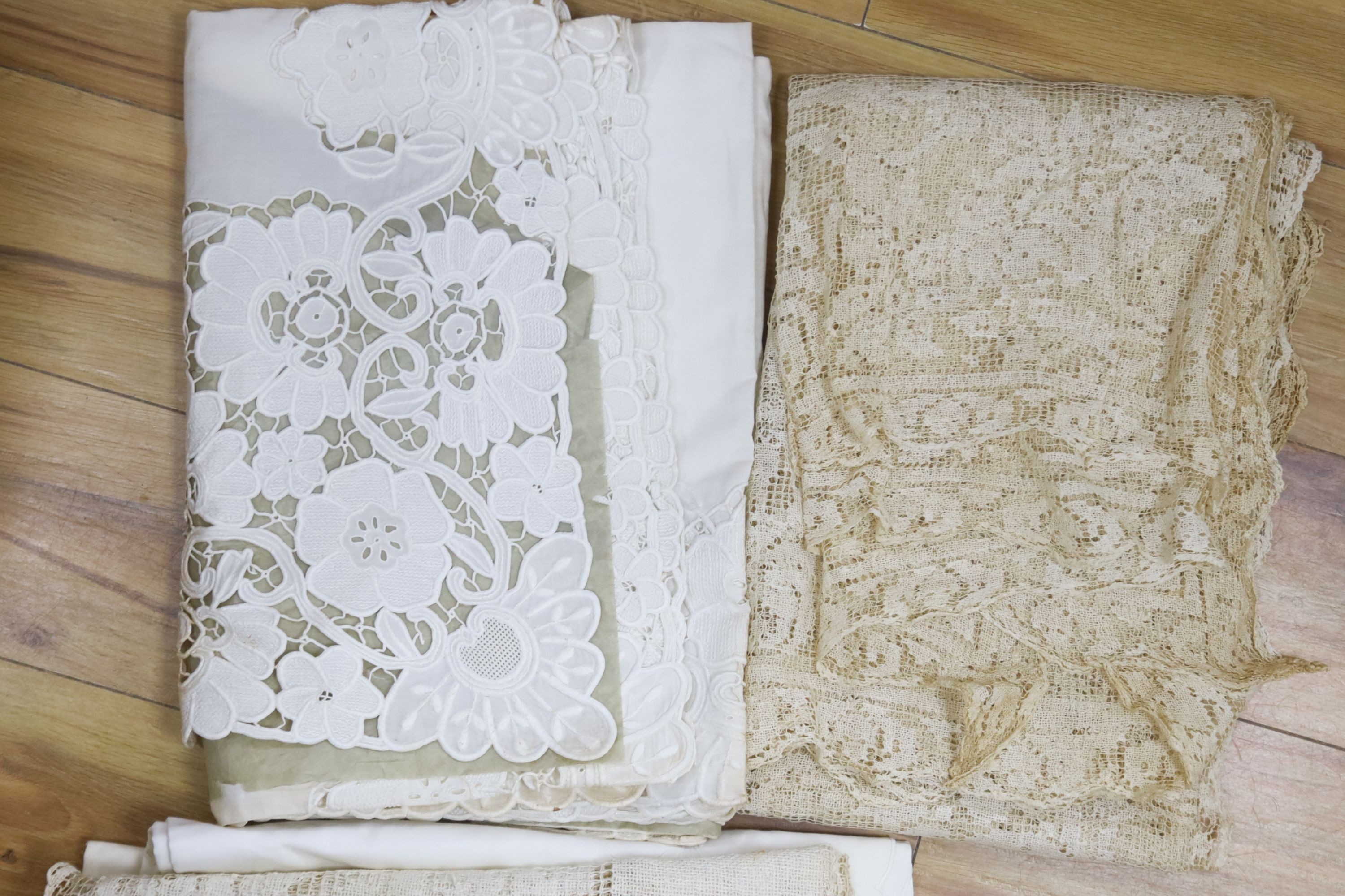 A collection of crochet edged linen tablecloths, a filet cloth and a 225cm long ornately cutworked cloth.
